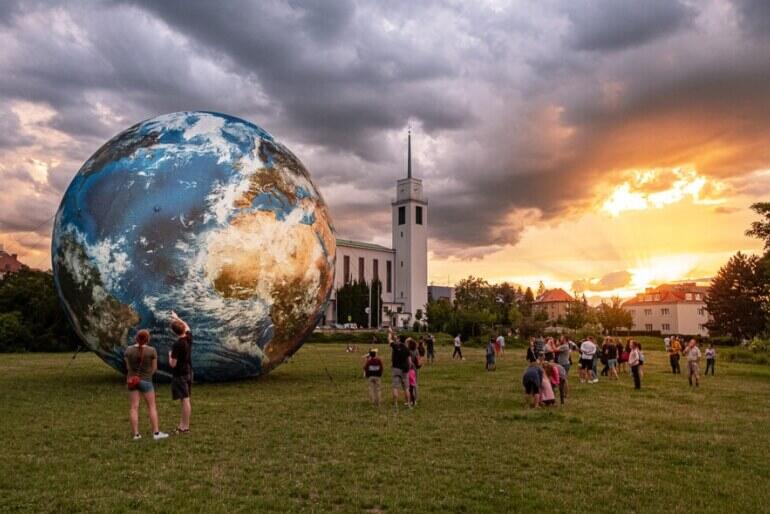 Obří fotorealistický model planety Země s názvem Terralóna vystavený v parku na brněnské Kraví hoře. Návštěvníci Festivalu planet obdivují instalaci během dramatického západu slunce. KULTINO*
