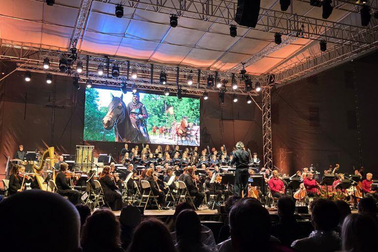 Skladatel a dirigent Jan Valta vede Filharmonii Brno na pódiu Festivalu Špilberk za doprovodu multimediální projekce ze hry Kingdom Come II. KULTINO*