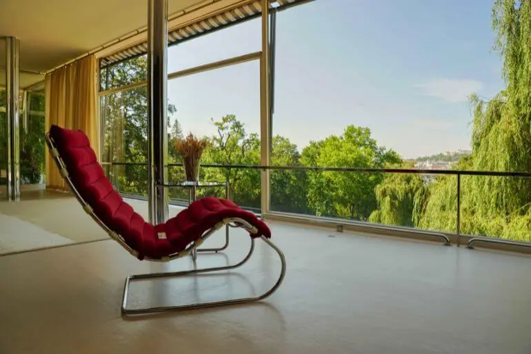 Ikonické červené lehátko v proskleném interiéru slavné brněnské vily Tugendhat s výhledem do zeleně. Toto architektonické dědictví města otevírá své dveře veřejnosti během kulturní události Noc literatury. KULTINO*