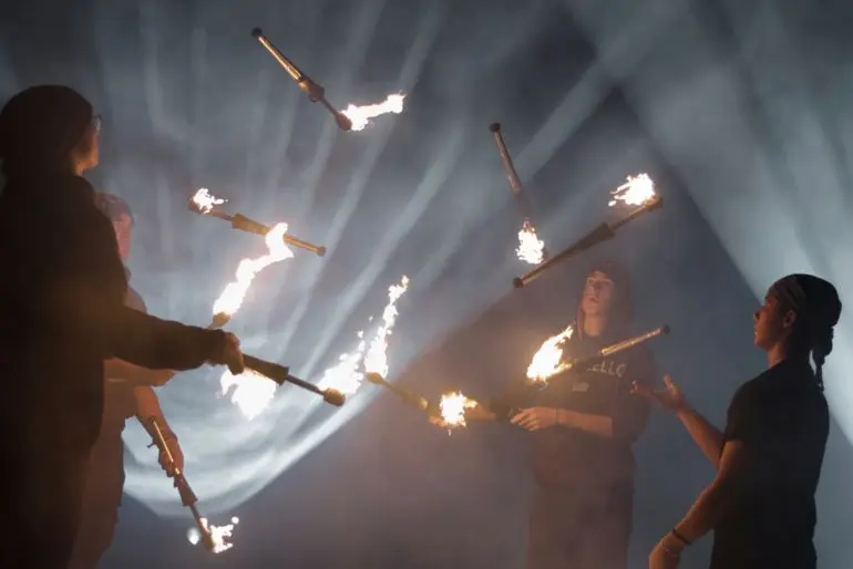 Žongléři s hořícími kužely při ohňové show v kouři a světle reflektorů. Doprovodný program lampionových průvodů Lužánek v Brně. KULTINO*