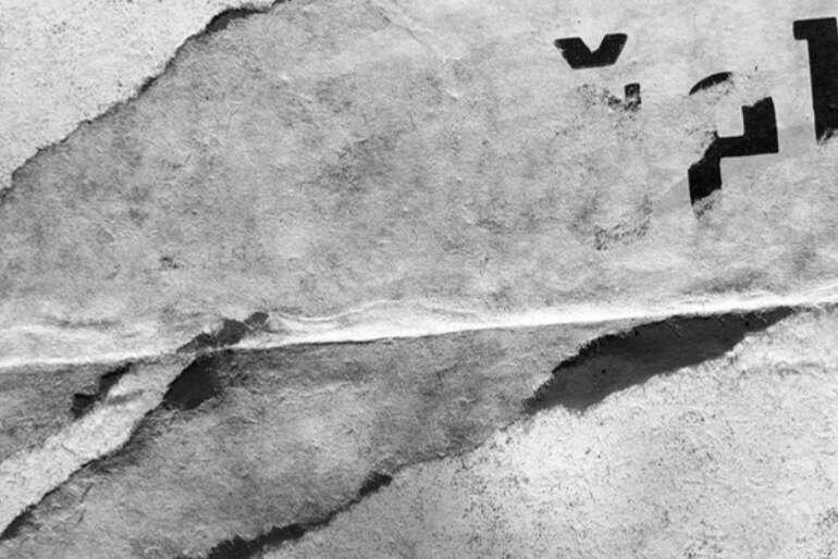 Černobílá fotografie potrhaného plakátu od Miroslava Myšky z výstavy Tváře a struktury v Moravské galerii. KULTINO*